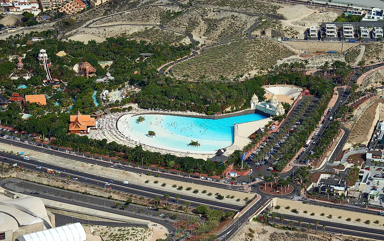 Aerial view of Siam Park with its large wave pool surrounded by gardens and the road below